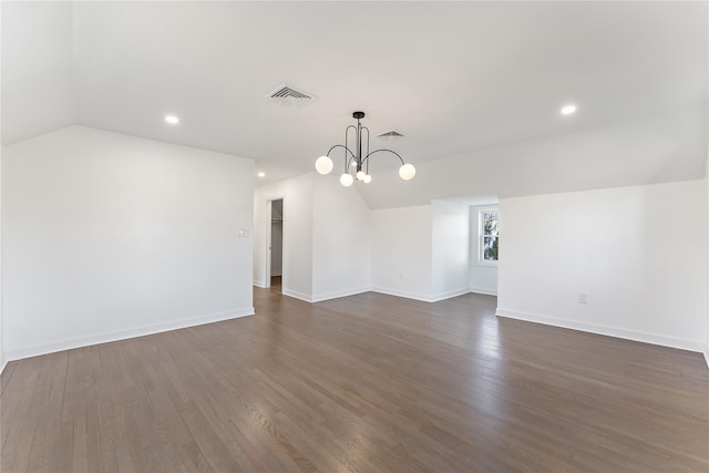 empty room featuring a notable chandelier, lofted ceiling, and dark wood-type flooring