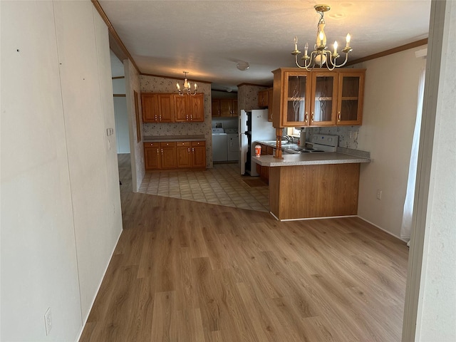 kitchen with a notable chandelier, decorative light fixtures, kitchen peninsula, and washing machine and clothes dryer