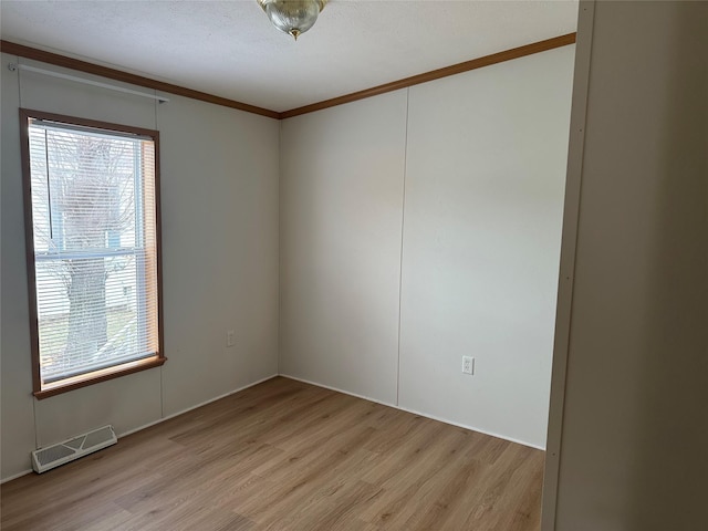 empty room featuring light wood-type flooring, plenty of natural light, and crown molding