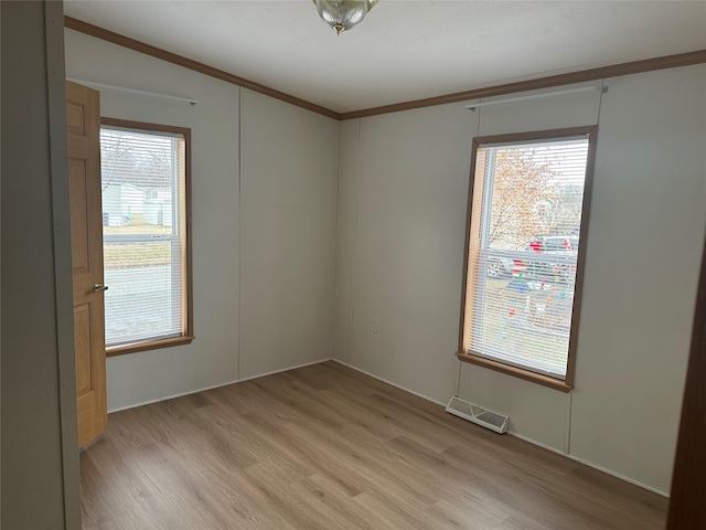 empty room with light wood-type flooring and crown molding