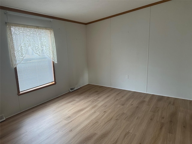 empty room with crown molding and light hardwood / wood-style flooring