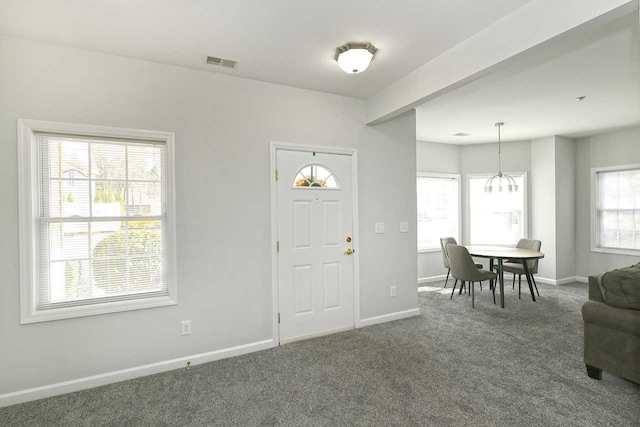 entrance foyer featuring dark carpet and an inviting chandelier