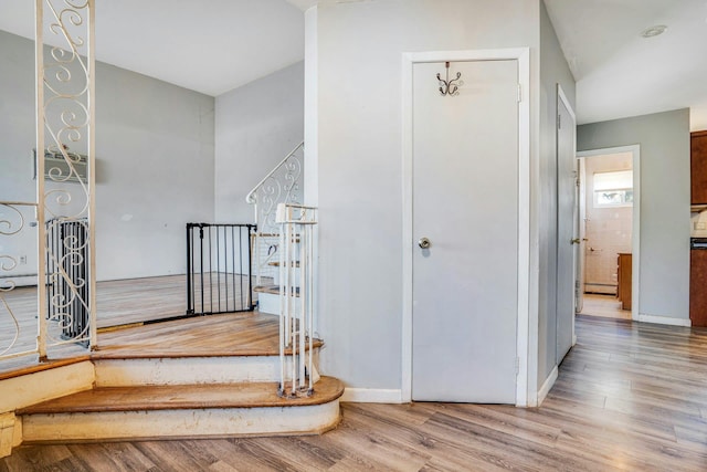 staircase with hardwood / wood-style floors and a baseboard radiator