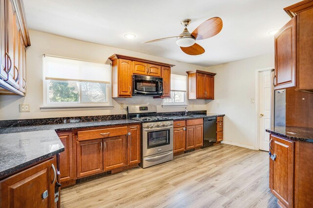 kitchen with ceiling fan, sink, dark stone countertops, black appliances, and light wood-type flooring