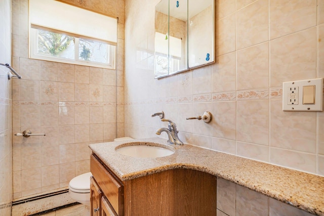 bathroom with vanity, toilet, tile walls, and a baseboard heating unit