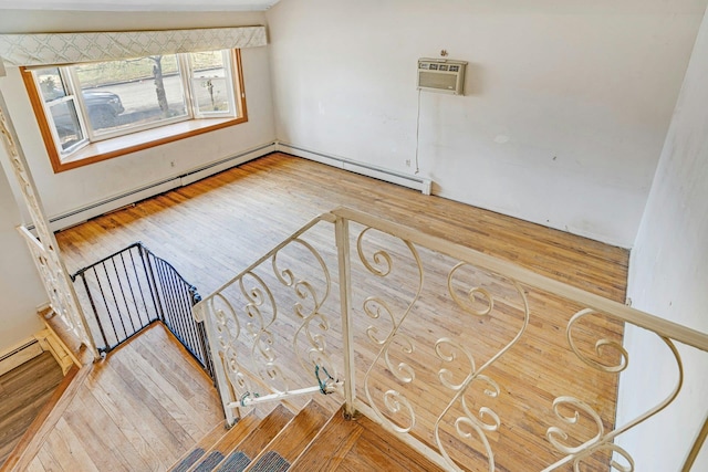 interior space with hardwood / wood-style flooring, a wall unit AC, and a baseboard heating unit