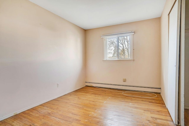 empty room with baseboard heating and light wood-type flooring