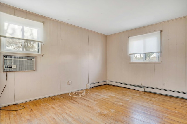 empty room featuring a wall mounted AC, wood walls, and light wood-type flooring