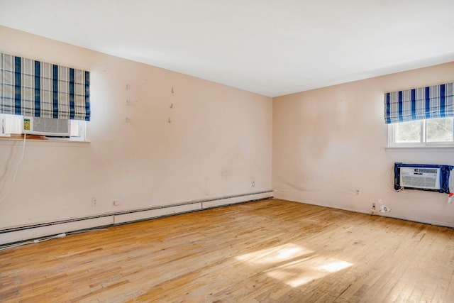 unfurnished room with light hardwood / wood-style floors, a wall unit AC, and a baseboard heating unit