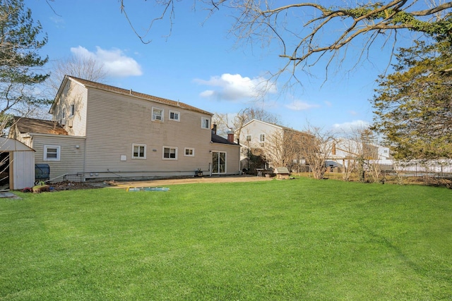 rear view of property featuring a storage unit and a yard