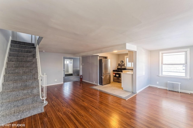 unfurnished living room with wood-type flooring and radiator heating unit