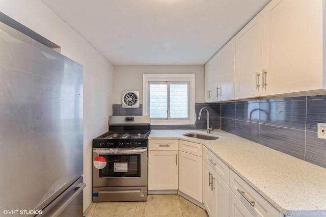 kitchen with backsplash, light stone counters, stainless steel appliances, sink, and white cabinetry