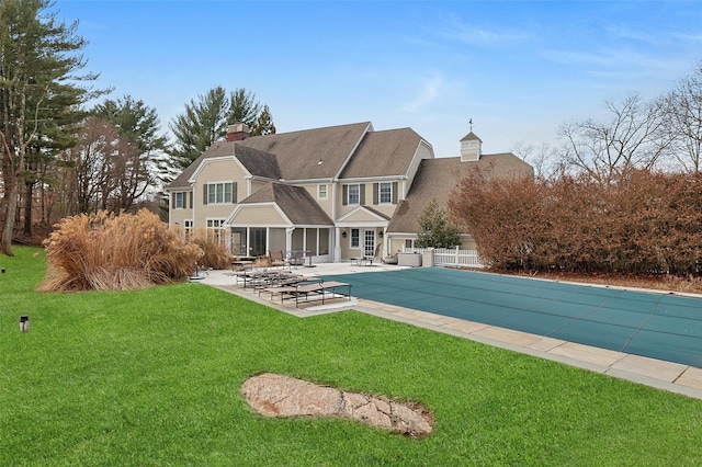 view of swimming pool featuring a yard, a patio area, fence, and a covered pool