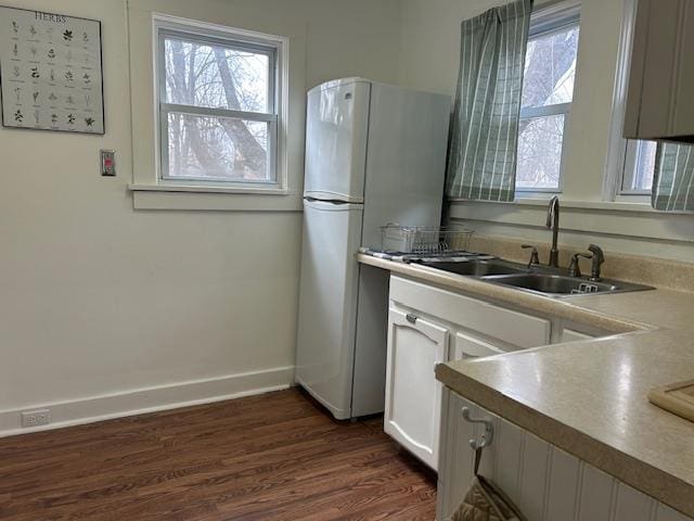 kitchen with white cabinets, dark hardwood / wood-style floors, white refrigerator, and sink