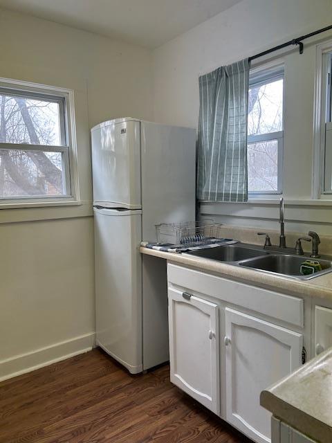 kitchen featuring sink, a healthy amount of sunlight, dark hardwood / wood-style floors, white refrigerator, and white cabinets