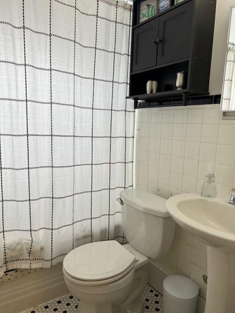 bathroom with tile patterned flooring, curtained shower, toilet, and tile walls