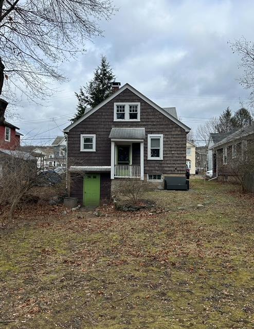 back of property with a lawn and covered porch