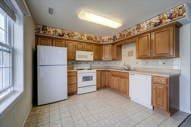 kitchen with light tile patterned floors, white appliances, a wealth of natural light, and sink