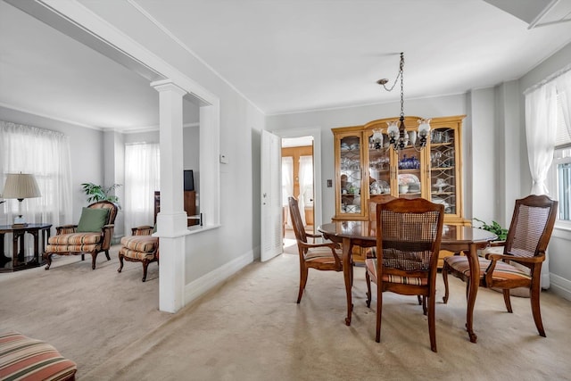 dining space featuring a notable chandelier, light colored carpet, and decorative columns