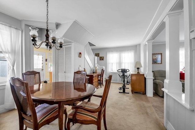 carpeted dining space featuring ornate columns and a chandelier