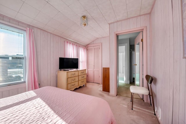 carpeted bedroom with wood walls, lofted ceiling, and a closet