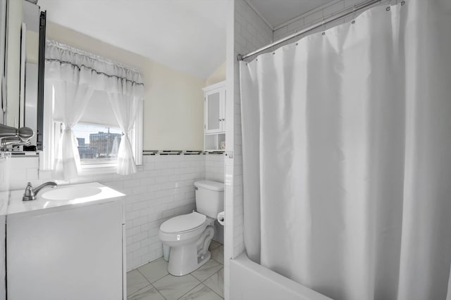 full bathroom featuring vanity, vaulted ceiling, shower / bath combo with shower curtain, tile walls, and toilet