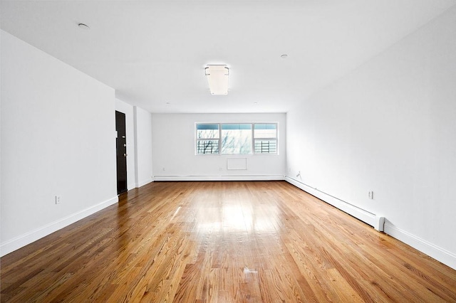 spare room with a baseboard radiator and hardwood / wood-style flooring