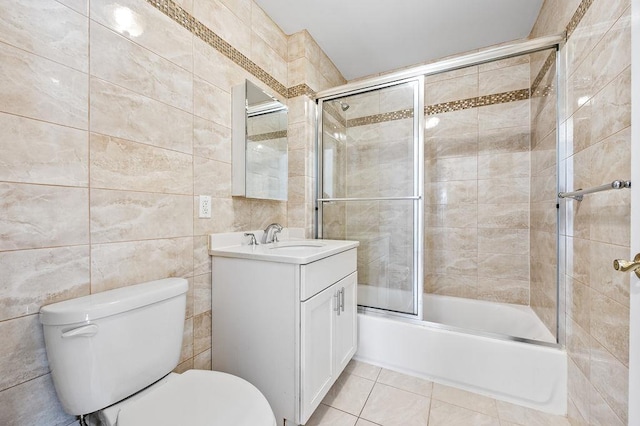 full bathroom with enclosed tub / shower combo, tile patterned floors, toilet, vanity, and tile walls