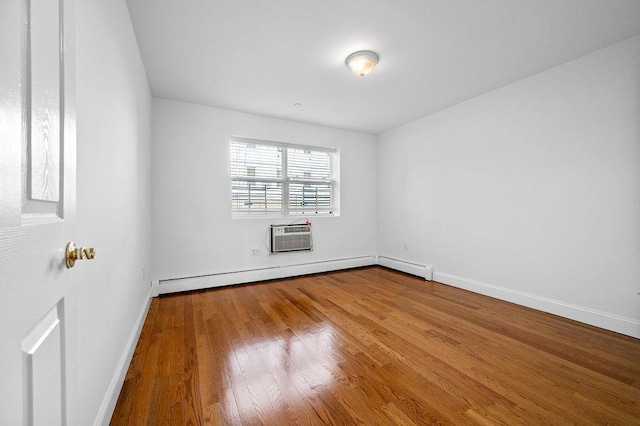 empty room featuring baseboard heating, wood-type flooring, and a wall mounted air conditioner