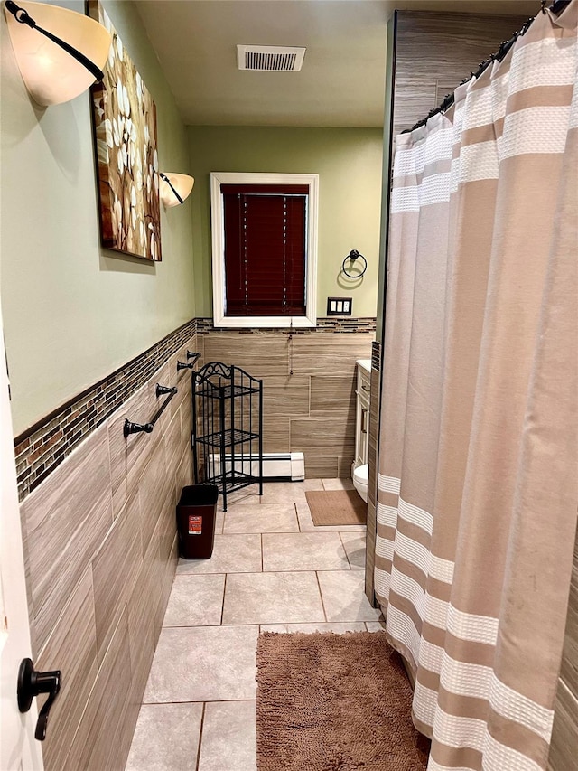 bathroom with tile patterned flooring, toilet, tile walls, and a baseboard heating unit