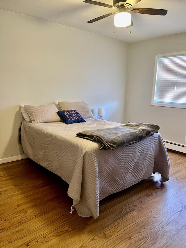 bedroom with hardwood / wood-style floors, ceiling fan, and baseboard heating