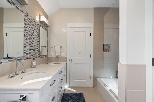 bathroom with vaulted ceiling, tile patterned flooring, a tub to relax in, tile walls, and vanity