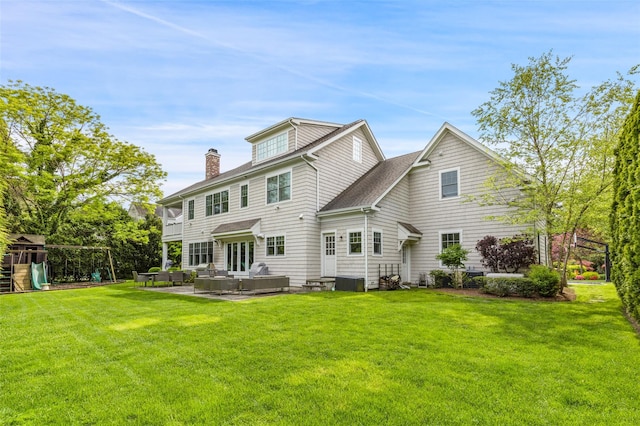 rear view of property featuring a yard, a playground, an outdoor living space, and a patio