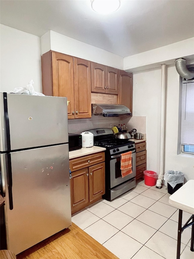 kitchen featuring decorative backsplash, light tile patterned floors, stainless steel appliances, and ventilation hood