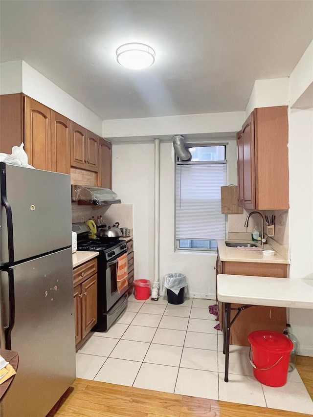 kitchen with stainless steel refrigerator, sink, tasteful backsplash, black range with gas stovetop, and light tile patterned floors