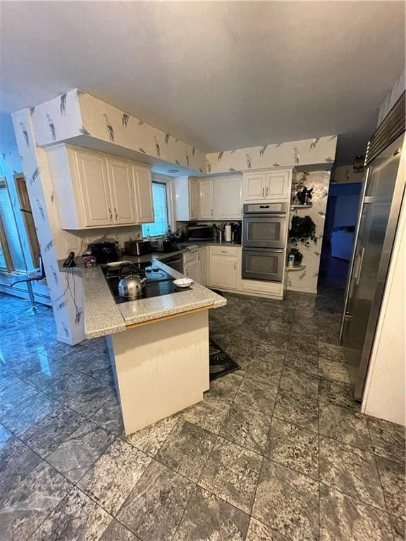 kitchen featuring white cabinets, a kitchen breakfast bar, sink, double oven, and kitchen peninsula