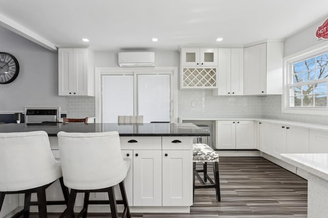 kitchen featuring white cabinetry, a breakfast bar area, and an AC wall unit