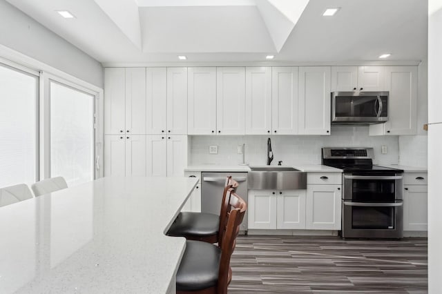 kitchen featuring tasteful backsplash, sink, white cabinets, and stainless steel appliances