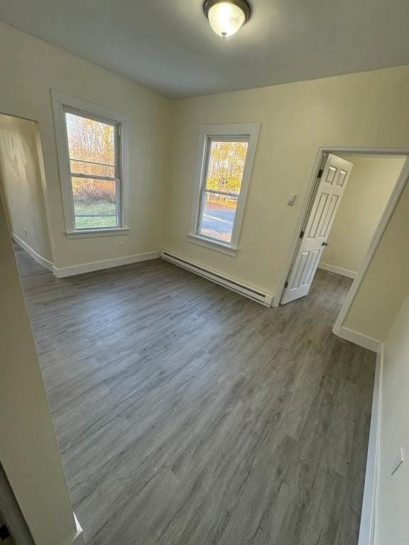 empty room with dark hardwood / wood-style floors and baseboard heating