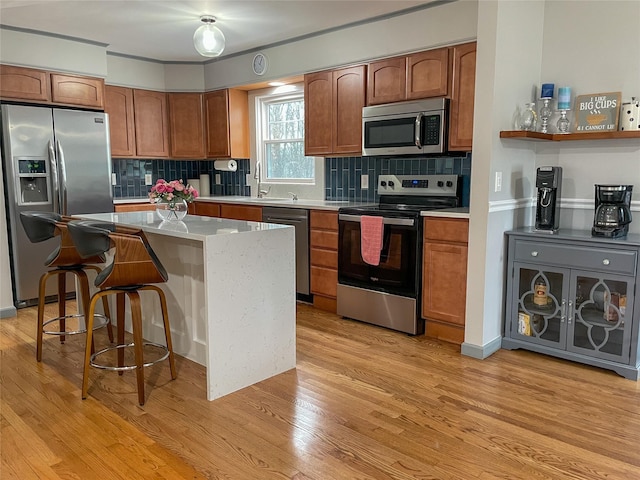 kitchen with appliances with stainless steel finishes, sink, a center island, light hardwood / wood-style floors, and a breakfast bar area