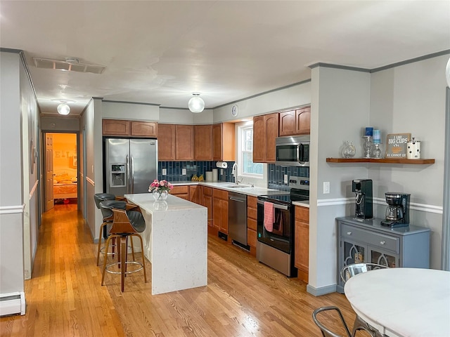 kitchen featuring a breakfast bar, decorative backsplash, baseboard heating, a kitchen island, and stainless steel appliances