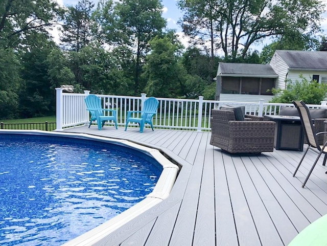 view of swimming pool featuring a deck and a sunroom