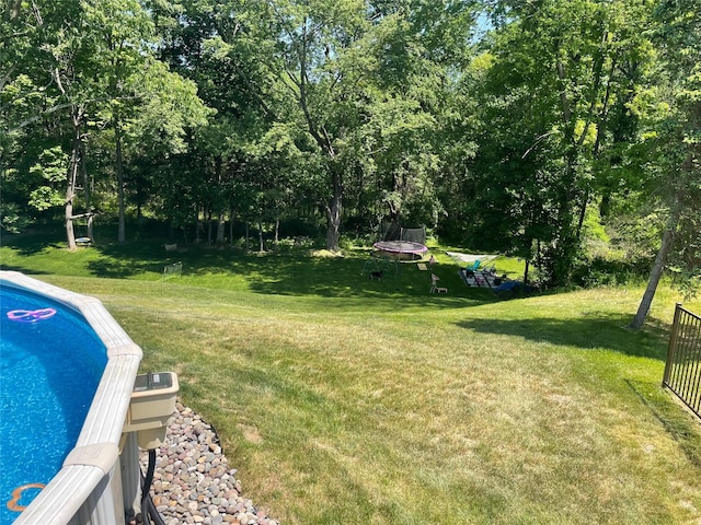 view of pool featuring a lawn and a trampoline