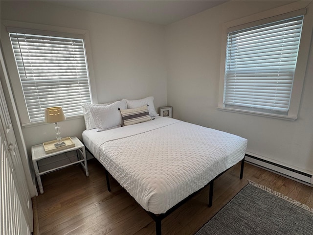 bedroom with a baseboard heating unit and dark hardwood / wood-style floors