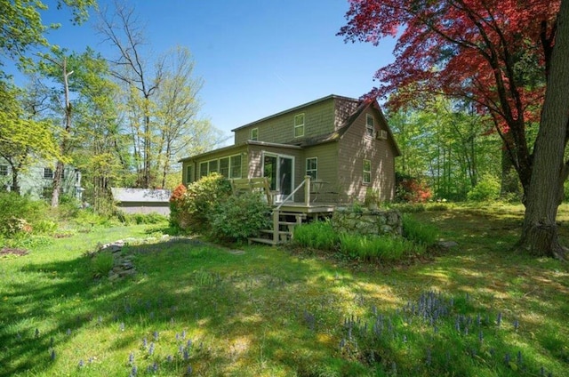 rear view of house featuring a wooden deck and a lawn