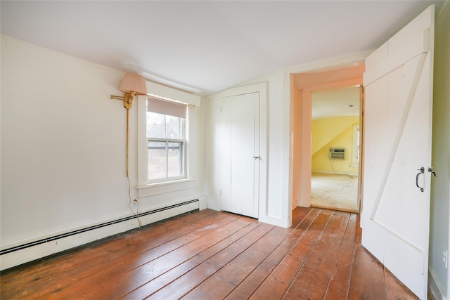 spare room featuring lofted ceiling, a baseboard heating unit, a wall mounted AC, and dark hardwood / wood-style floors