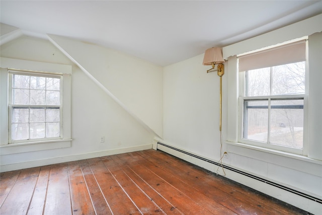 additional living space with dark hardwood / wood-style floors, a wealth of natural light, and baseboard heating