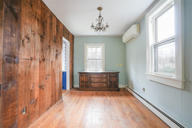 empty room featuring an inviting chandelier, a baseboard radiator, a wall mounted air conditioner, and light hardwood / wood-style floors