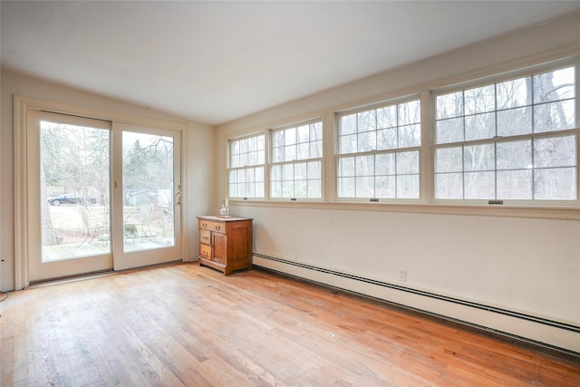 unfurnished room with baseboard heating, lofted ceiling, and light hardwood / wood-style floors