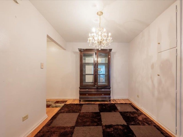 unfurnished dining area featuring wood-type flooring and a chandelier